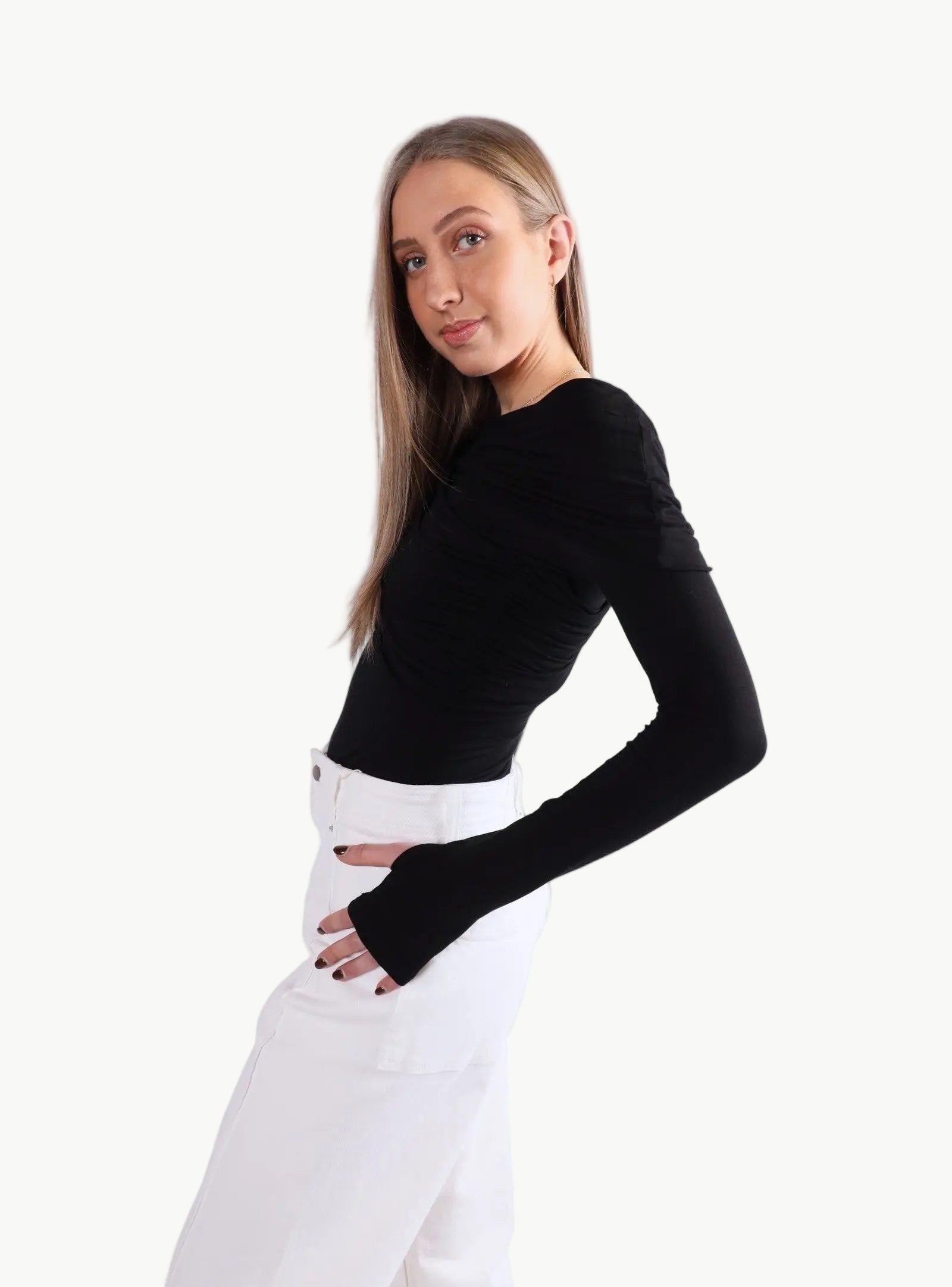 La Libéré model  wearing a black long-sleeve top and white pants on a light gray background