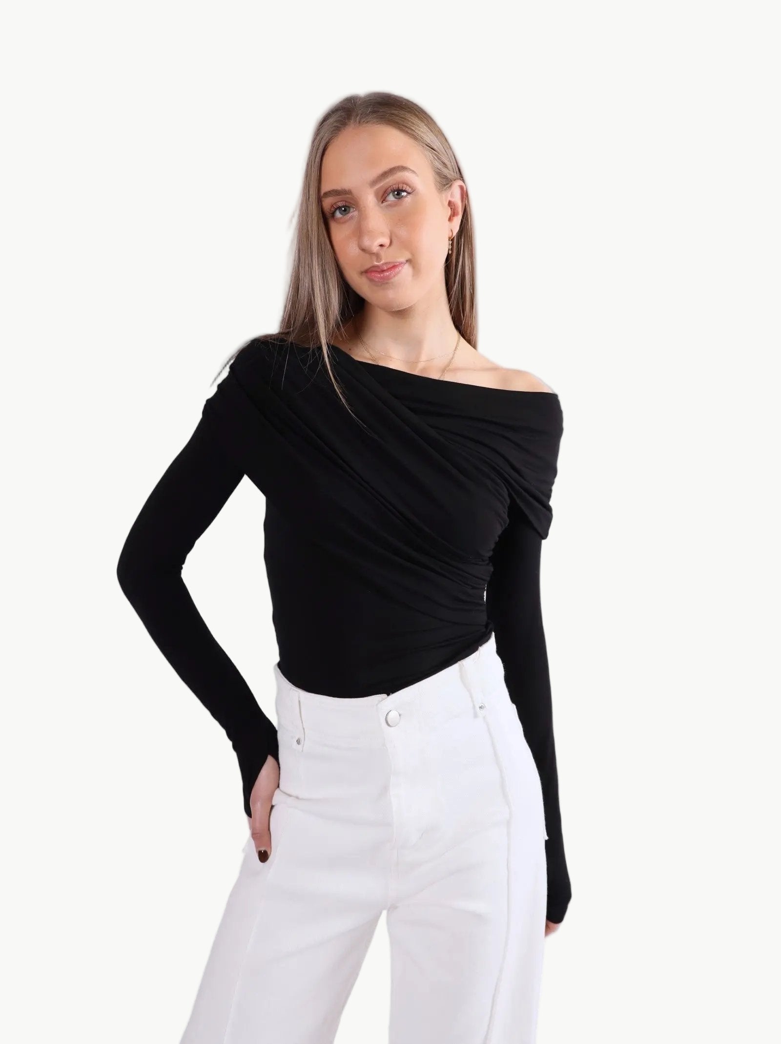 La Libéré model  wearing a black off-shoulder top and white pants on a light gray background