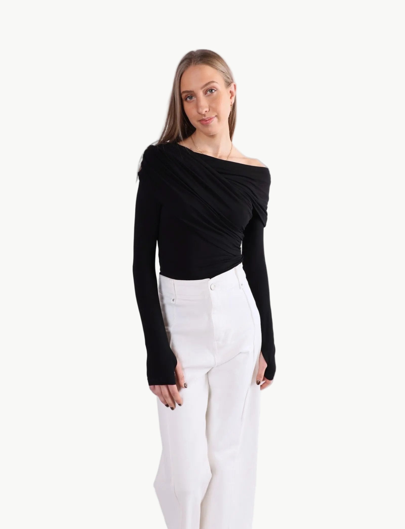 La Libéré model  wearing a black off-shoulder top and white pants on a white background