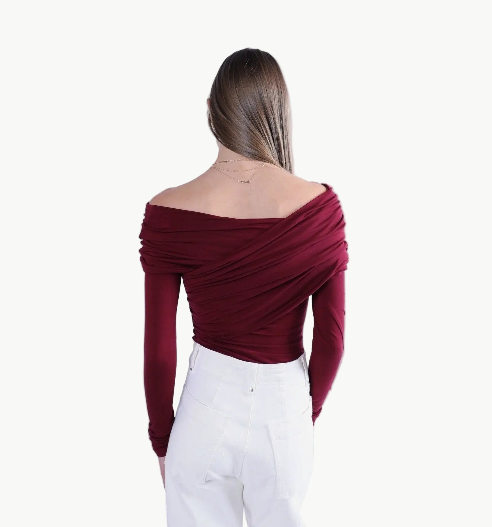 La Libéré model  wearing a burgundy off-shoulder top and white pants on a white background