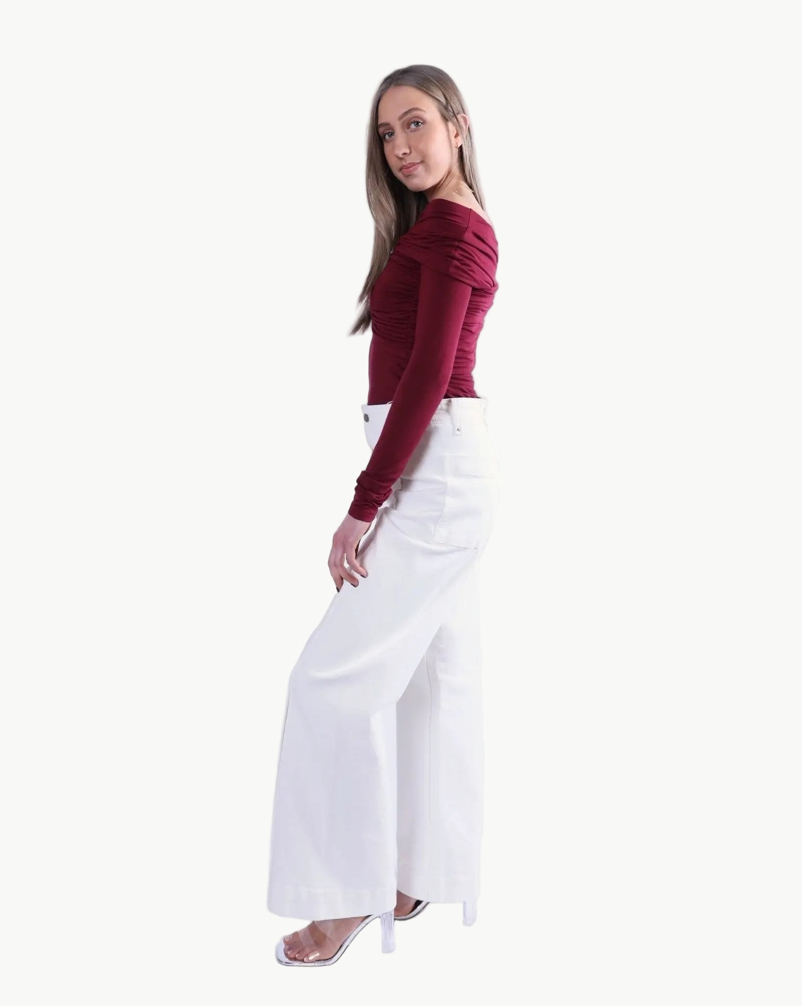 La Libéré model wearing a burgundy top and white pants on a white background